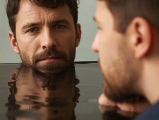 man looking at reflection in mirror of different parts